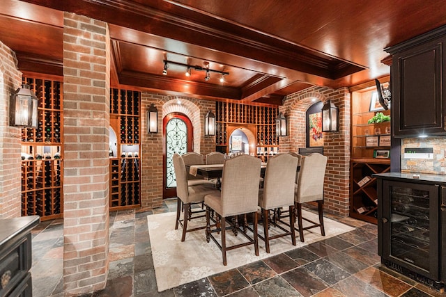 7N230 Sims Ln, Saint Charles, IL 60175 - wine room featuring beverage cooler, stone tile floors, crown molding, brick wall, and rail lighting
