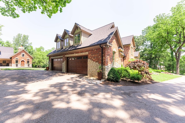7N230 Sims Ln, Saint Charles, IL 60175 - view of home's exterior featuring stone siding, driveway, roof with shingles, an attached garage, and brick siding