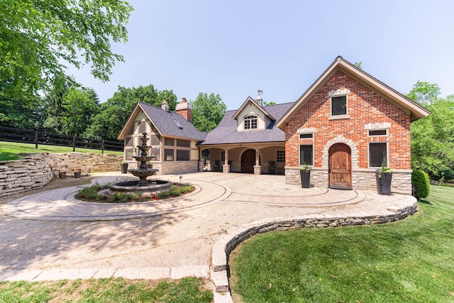 7N230 Sims Ln, Saint Charles, IL 60175 - view of front of property featuring curved driveway, a chimney, stone siding, brick siding, and a patio area