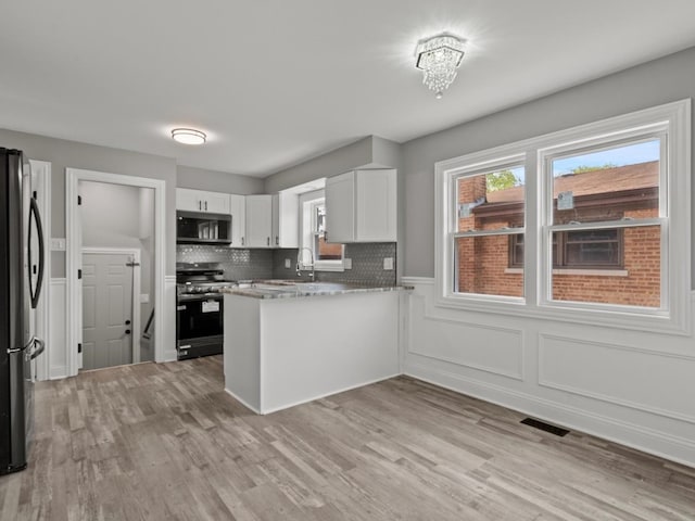15035 Evers St, Dolton, IL 60419 - kitchen featuring stainless steel appliances, a peninsula, white cabinets, healthy amount of natural light, and wainscoting