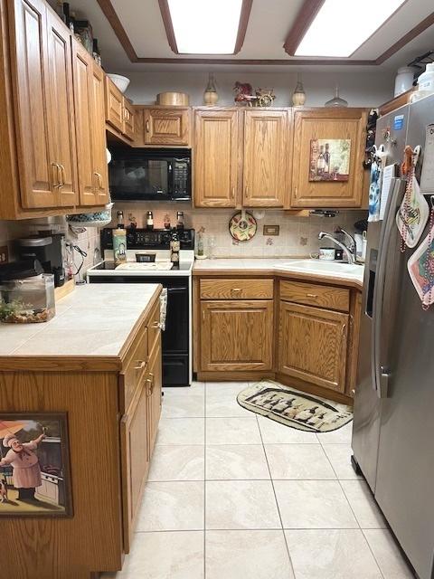 6700 S Brainard Ave Unit 223, Countryside, IL 60525 - kitchen with black microwave, stainless steel fridge, range with electric stovetop, light tile patterned flooring, and tile counters