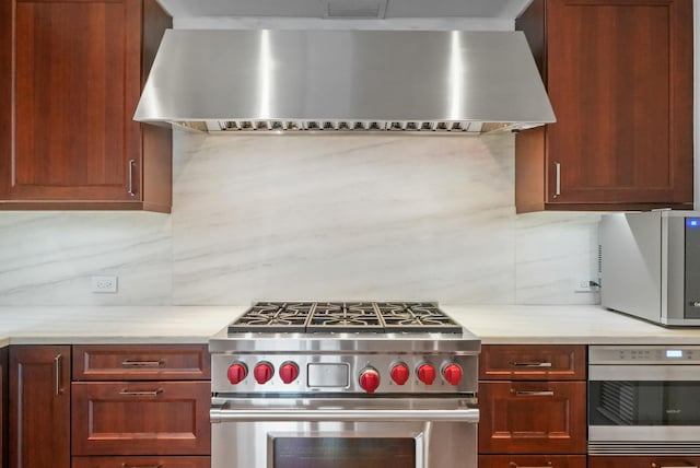 118 E Erie St Unit 14B, Chicago, IL 60611 - kitchen with stainless steel appliances, wall chimney range hood, light countertops, and tasteful backsplash