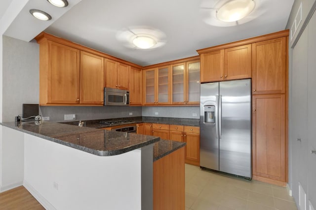 530 N Lake Shore Dr Unit 2408, Chicago, IL 60611 - kitchen featuring appliances with stainless steel finishes, a peninsula, glass insert cabinets, dark stone counters, and brown cabinetry
