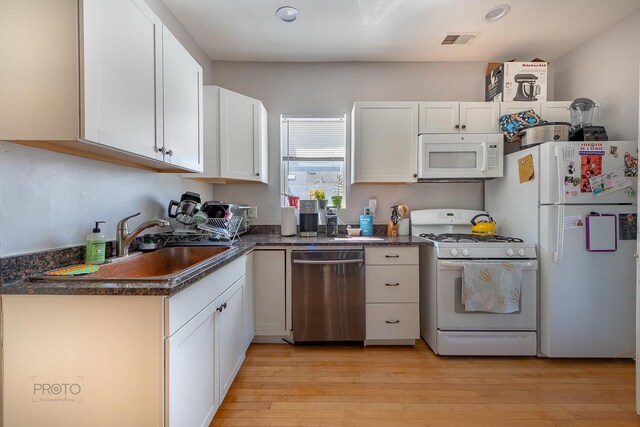 530 N Ashland Ave, Chicago, IL 60622 - kitchen featuring white appliances, dark countertops, light wood-style floors, white cabinets, and recessed lighting