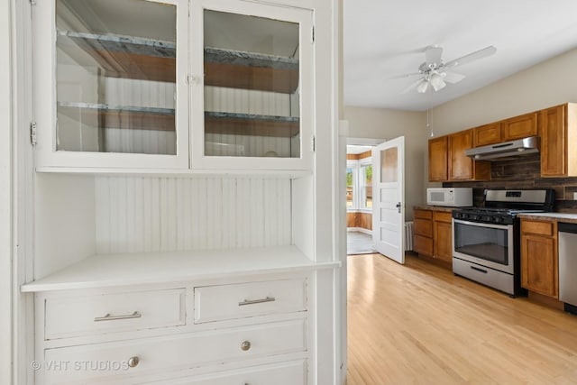 6208 N Artesian Ave, Chicago, IL 60659 - kitchen featuring stainless steel appliances, under cabinet range hood, brown cabinetry, and ceiling fan