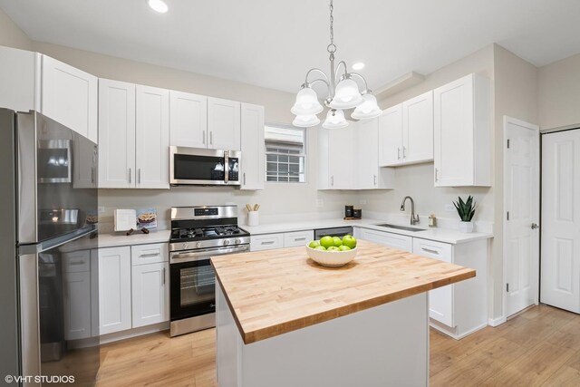 6317 W Cuyler Ave, Chicago, IL 60634 - kitchen featuring appliances with stainless steel finishes, wood counters, recessed lighting, a center island, and white cabinetry
