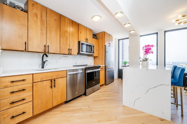 100 E Walton St Unit 38H, Chicago, IL 60611 - kitchen featuring stainless steel appliances, light wood-type flooring, a breakfast bar area, light stone countertops, and expansive windows