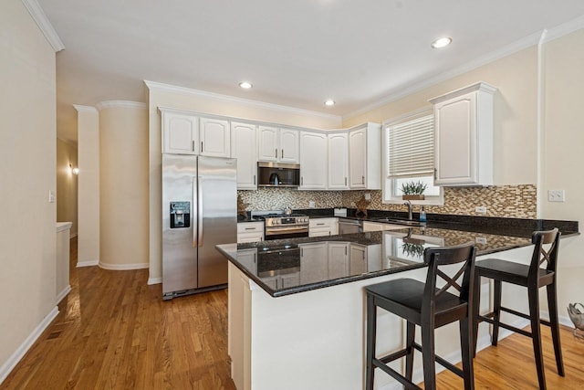 1720 W Diversey Pkwy Unit 1, Chicago, IL 60614 - kitchen featuring stainless steel appliances, decorative backsplash, white cabinetry, a kitchen breakfast bar, and ornamental molding