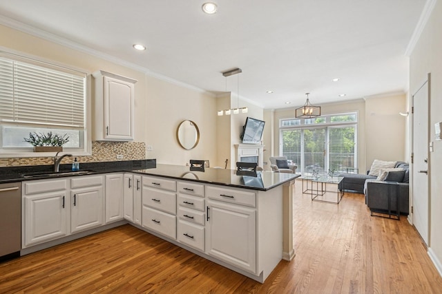 1720 W Diversey Pkwy Unit 1, Chicago, IL 60614 - kitchen with open floor plan, a peninsula, light wood-style floors, dark countertops, and crown molding
