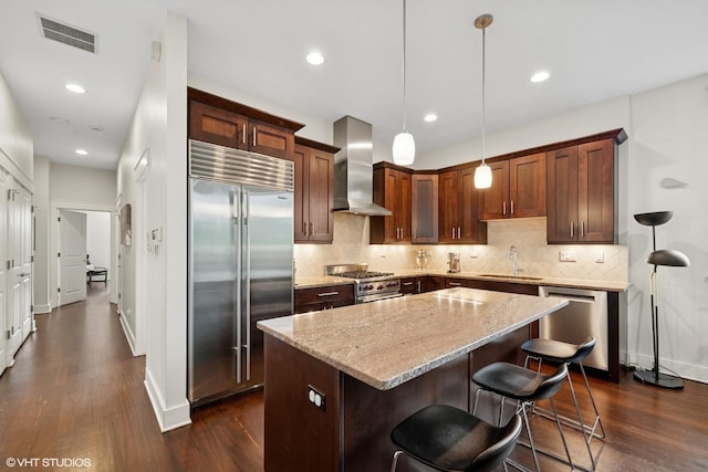 639 W Briar Pl Unit 4W, Chicago, IL 60657 - kitchen with high quality appliances, wall chimney exhaust hood, dark wood-type flooring, a kitchen island, and tasteful backsplash