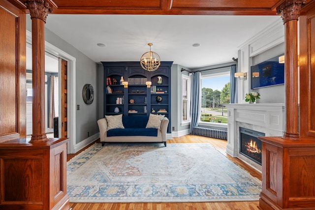 557 Garfield Ave, Aurora, IL 60506 - sitting room with wood finished floors, a glass covered fireplace, a chandelier, and decorative columns