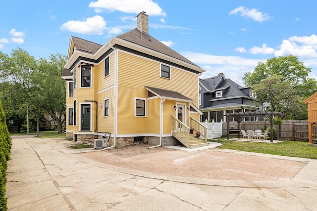 557 Garfield Ave, Aurora, IL 60506 - back of property featuring a chimney, a patio area, and a shingled roof