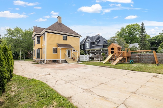 557 Garfield Ave, Aurora, IL 60506 - rear view of house featuring a playground, entry steps, and a chimney