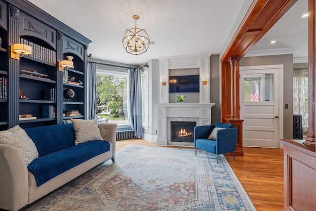 557 Garfield Ave, Aurora, IL 60506 - living area with radiator heating unit, a chandelier, light wood-style flooring, crown molding, and a fireplace
