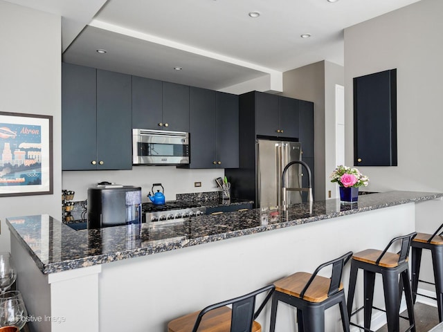 500 W Superior St Unit 1202, Chicago, IL 60654 - kitchen with appliances with stainless steel finishes, a breakfast bar area, dark stone counters, dark cabinets, and recessed lighting