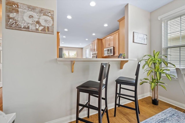 725 Bohannon Cir, Oswego, IL 60543 - kitchen featuring stainless steel appliances, light wood-style flooring, a breakfast bar, recessed lighting, and light countertops