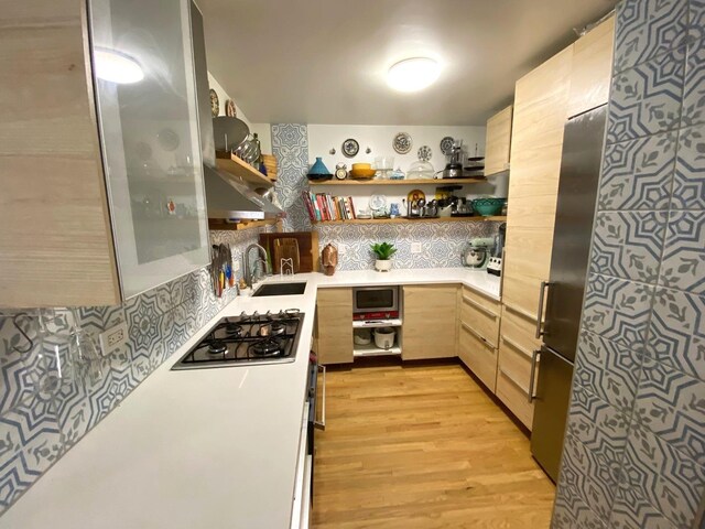 559 W Surf St Unit 101, Chicago, IL 60657 - kitchen with open shelves, stainless steel gas cooktop, light brown cabinetry, light countertops, and light wood-style floors