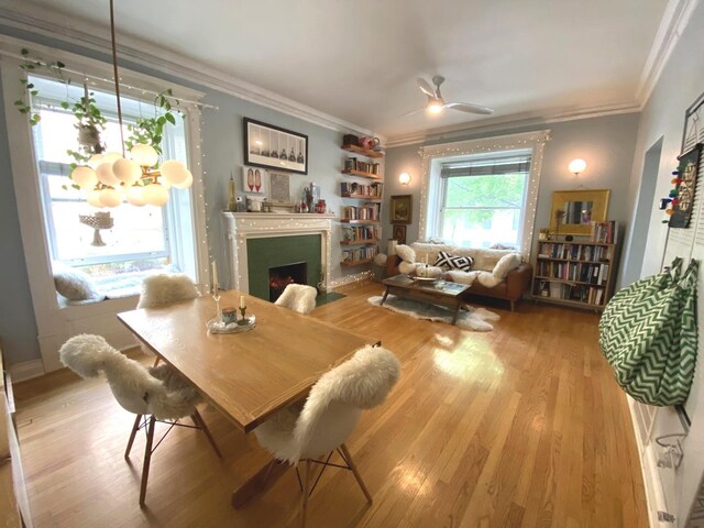 559 W Surf St Unit 101, Chicago, IL 60657 - dining space with a fireplace with flush hearth, crown molding, wood finished floors, and ceiling fan