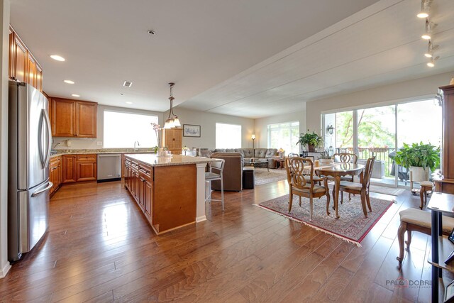1199 E Port Clinton Rd Unit 209, Vernon Hills, IL 60061 - kitchen with stainless steel appliances, brown cabinetry, hardwood / wood-style floors, a kitchen island, and hanging light fixtures