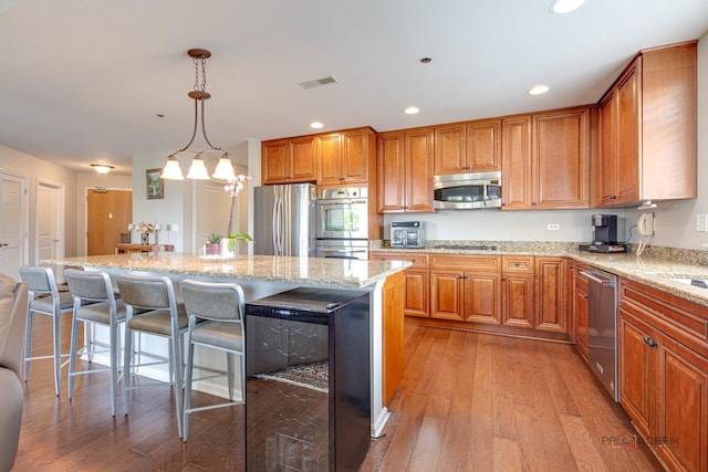 1199 E Port Clinton Rd Unit 209, Vernon Hills, IL 60061 - kitchen with appliances with stainless steel finishes, light wood-type flooring, light stone counters, a kitchen breakfast bar, and a kitchen island