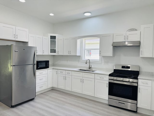 616 N Everett St, Streator, IL 61364 - kitchen with stainless steel appliances, under cabinet range hood, white cabinetry, light countertops, and light wood-type flooring