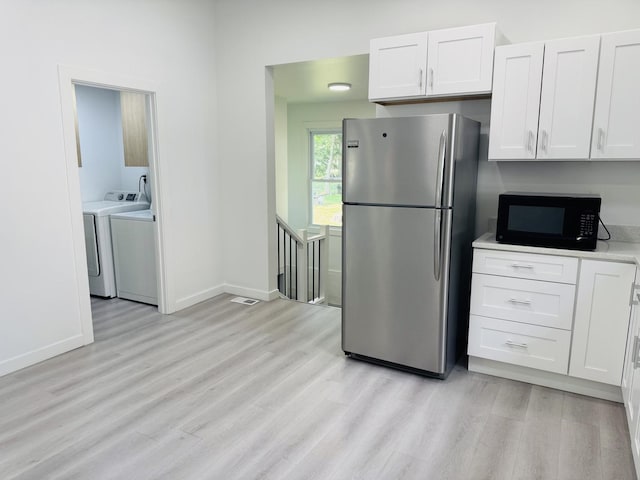 616 N Everett St, Streator, IL 61364 - kitchen featuring freestanding refrigerator, black microwave, washing machine and clothes dryer, and light wood-style floors