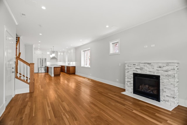 4133 N Kenmore Ave Unit 2S, Chicago, IL 60613 - unfurnished living room with ornamental molding, a stone fireplace, light wood-style flooring, stairway, and recessed lighting