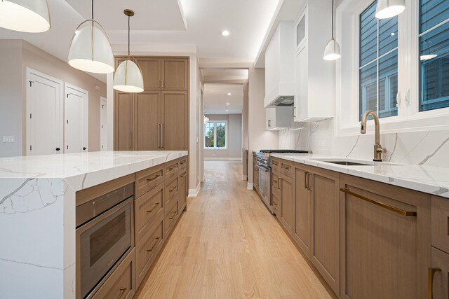 2218 W Oakdale Ave, Chicago, IL 60618 - kitchen with double oven range, light wood finished floors, brown cabinetry, light stone countertops, and decorative light fixtures