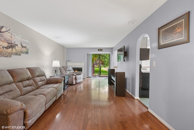 1521 S County Farm Rd Unit 1-3C, Wheaton, IL 60189 - living area with arched walkways, wood finished floors, and a warm lit fireplace