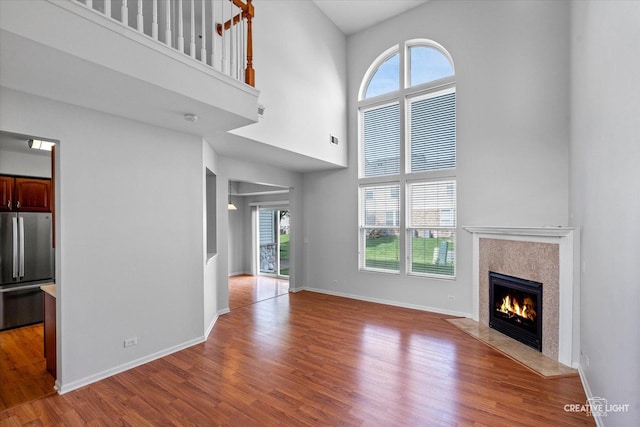 24825 W Gates Ct, Plainfield, IL 60585 - unfurnished living room featuring a towering ceiling, healthy amount of natural light, a fireplace, and wood finished floors