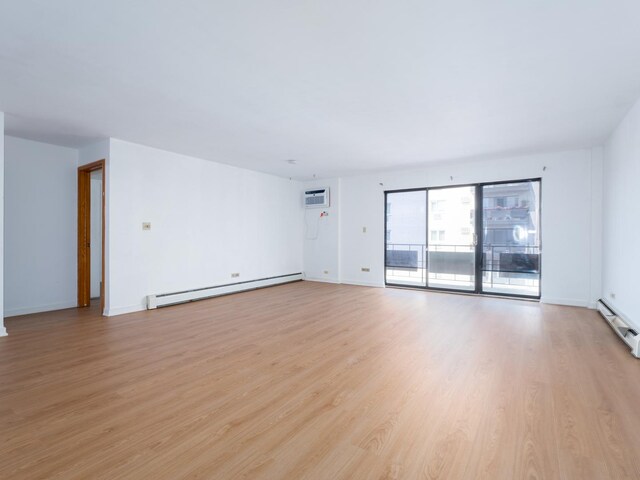 8005 W Oconnor Dr Unit 4E, River Grove, IL 60171 - empty room featuring baseboard heating, light wood finished floors, and a wall mounted air conditioner