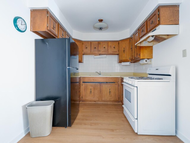 8005 W Oconnor Dr Unit 4E, River Grove, IL 60171 - kitchen featuring white gas range oven, freestanding refrigerator, under cabinet range hood, and brown cabinetry
