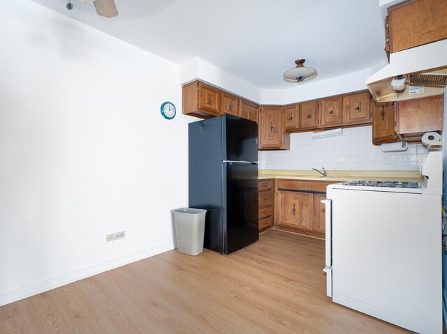 8005 W Oconnor Dr Unit 4E, River Grove, IL 60171 - kitchen with freestanding refrigerator, white range with gas stovetop, under cabinet range hood, light wood finished floors, and brown cabinetry