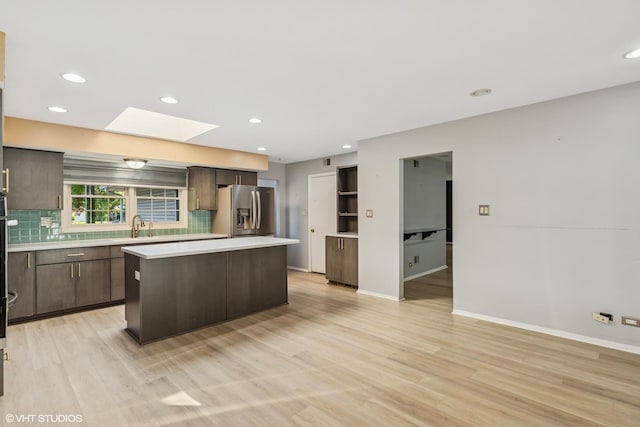 3071 Plum Island Dr, Northbrook, IL 60062 - kitchen featuring stainless steel refrigerator with ice dispenser, a skylight, light countertops, dark brown cabinets, and a kitchen island