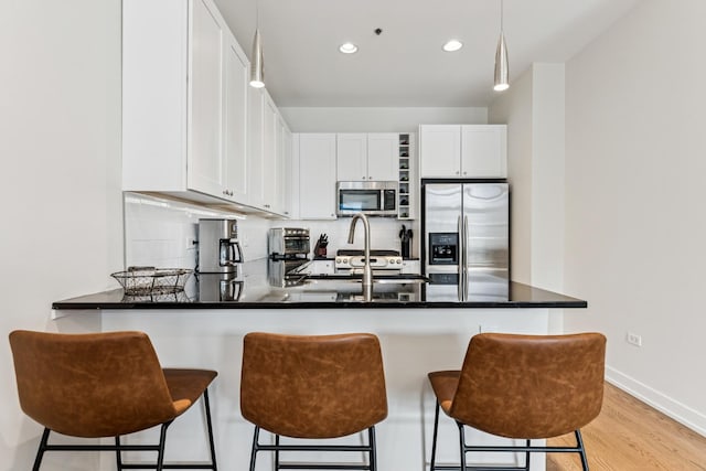150 W Superior St Unit 1103, Chicago, IL 60654 - kitchen featuring stainless steel appliances, a peninsula, decorative backsplash, white cabinetry, and light wood-type flooring