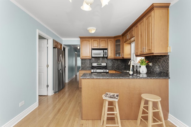 4567 N Merrimac Ave, Chicago, IL 60630 - kitchen featuring appliances with stainless steel finishes, a peninsula, tasteful backsplash, light wood-type flooring, and ornamental molding