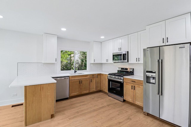 5216 Arlington Cir, Hanover Park, IL 60133 - kitchen featuring appliances with stainless steel finishes, a peninsula, decorative backsplash, light wood finished floors, and recessed lighting