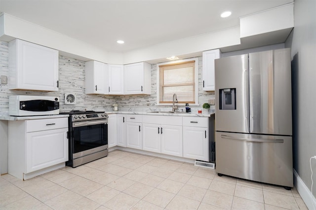 1006 S Adelaide St, Normal, IL 61761 - kitchen with appliances with stainless steel finishes, light countertops, decorative backsplash, white cabinets, and light tile patterned floors