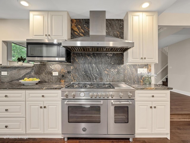 2S578 Patrick Henry Sq Unit 578, Oak Brook, IL 60523 - kitchen featuring stainless steel appliances, wall chimney exhaust hood, backsplash, wood finished floors, and dark stone counters