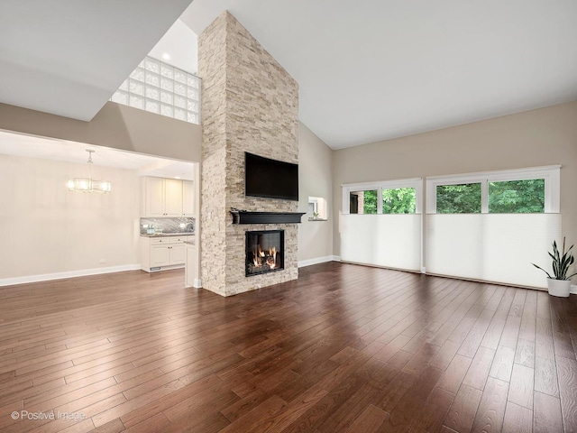 2S578 Patrick Henry Sq Unit 578, Oak Brook, IL 60523 - unfurnished living room featuring high vaulted ceiling, a chandelier, a stone fireplace, and dark wood-type flooring