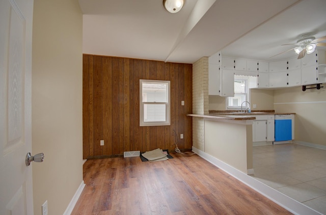 1318 N Prairie Ave, Joliet, IL 60435 - kitchen with a peninsula, ceiling fan, wood walls, white cabinetry, and light wood-style flooring