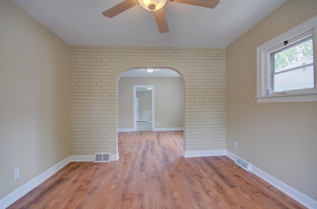 1318 N Prairie Ave, Joliet, IL 60435 - spare room featuring ceiling fan, wood finished floors, arched walkways, a textured ceiling, and brick wall