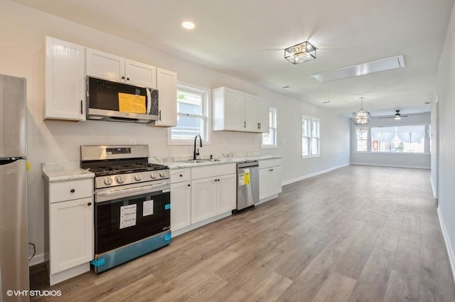 2155 N Mobile Ave, Chicago, IL 60639 - kitchen with appliances with stainless steel finishes, white cabinets, light wood-type flooring, open floor plan, and recessed lighting