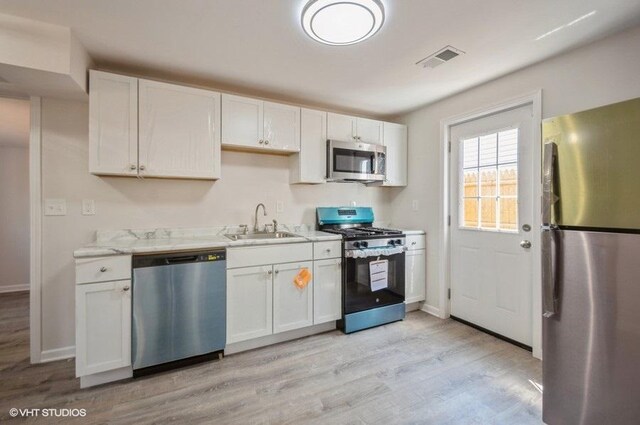 2155 N Mobile Ave, Chicago, IL 60639 - kitchen featuring appliances with stainless steel finishes, light wood finished floors, white cabinets, and light stone countertops