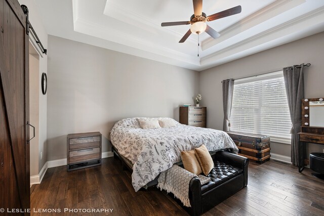 565 Sudbury Cir Unit 0, Oswego, IL 60543 - bedroom with a barn door, a tray ceiling, ornamental molding, dark wood finished floors, and ceiling fan