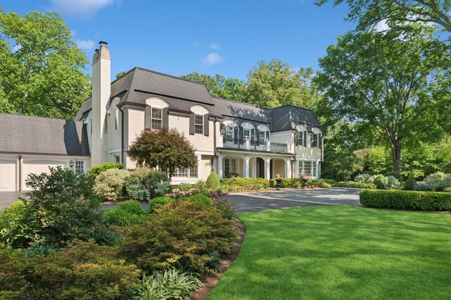 611 Oak Knoll Dr, Lake Forest, IL 60045 - rear view of house featuring a balcony, a yard, mansard roof, a chimney, and a shingled roof