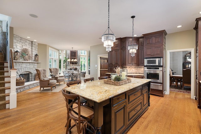 1091 Johnson Dr, Naperville, IL 60540 - kitchen with stainless steel appliances, a chandelier, a warming drawer, a fireplace, and light wood finished floors