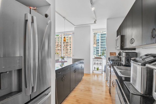 8 E Randolph St Unit 1401, Chicago, IL 60601 - kitchen with appliances with stainless steel finishes, light wood finished floors, rail lighting, dark stone countertops, and dark cabinetry