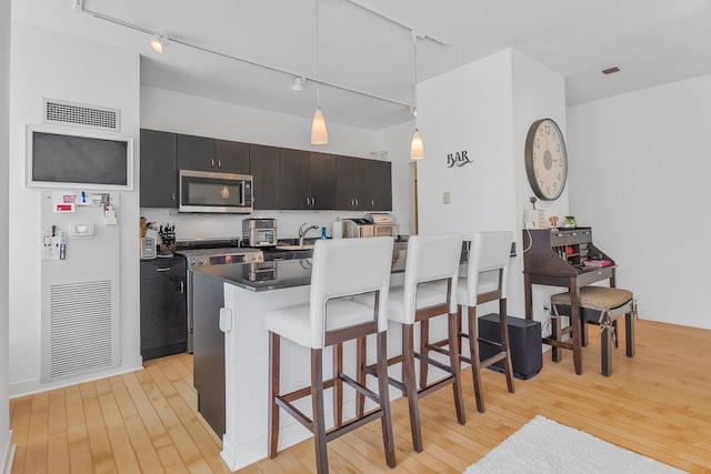 8 E Randolph St Unit 1401, Chicago, IL 60601 - kitchen with stainless steel microwave, track lighting, dark countertops, and light wood-style flooring