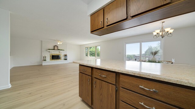 1320 Lake Summerset Rd, Davis, IL 61019 - kitchen featuring a fireplace, light wood-style flooring, brown cabinetry, ceiling fan, and a chandelier
